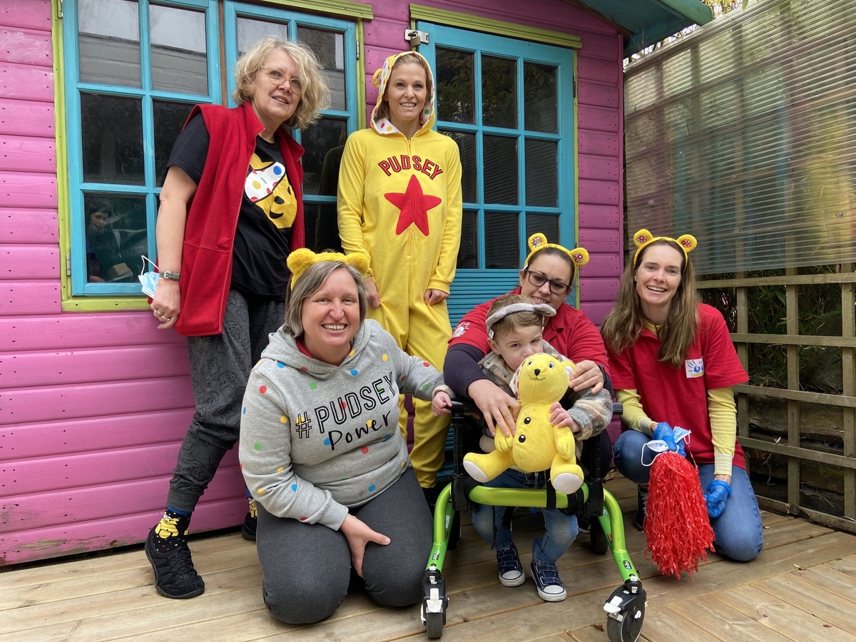 Playskill team members wearing Children In Need themed outfits, and a child holding a Pudsey soft toy