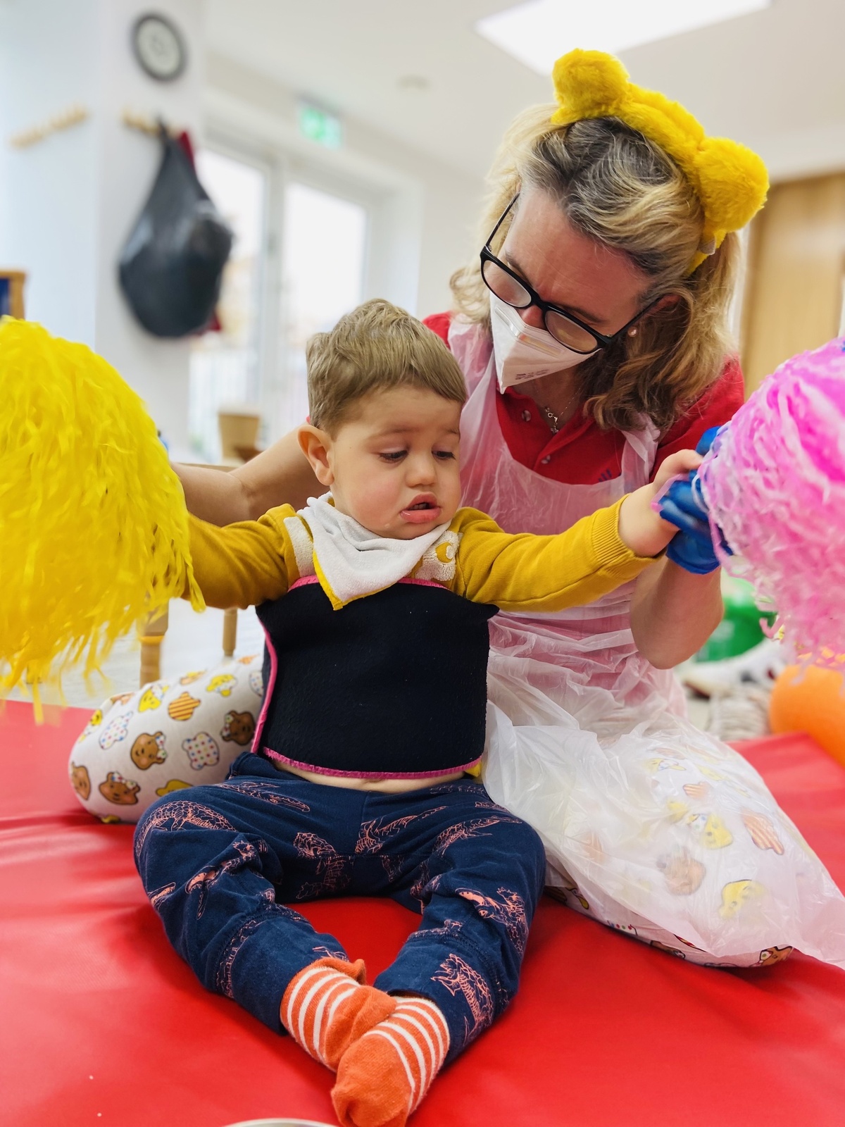 Child playing with some pom-poms, with help from a Playskill physio